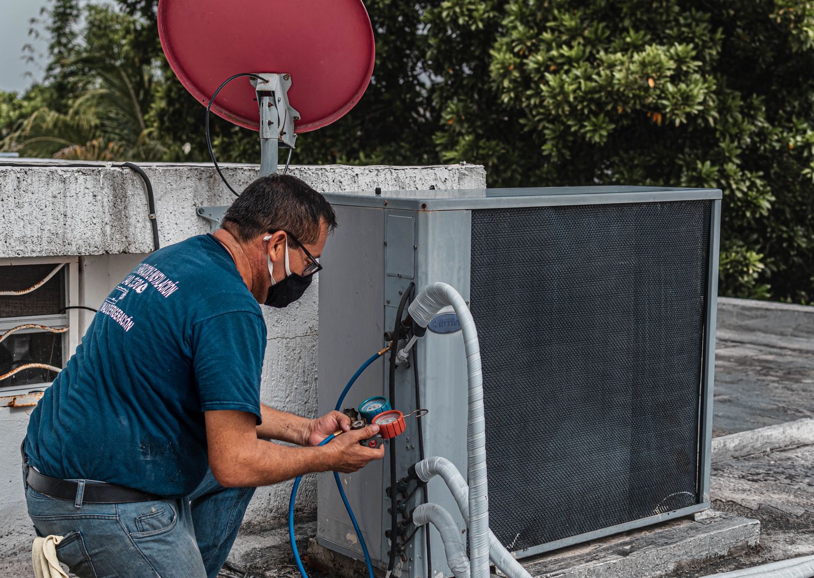 Technician using a manifold gauge to service a rooftop air conditioning unit
